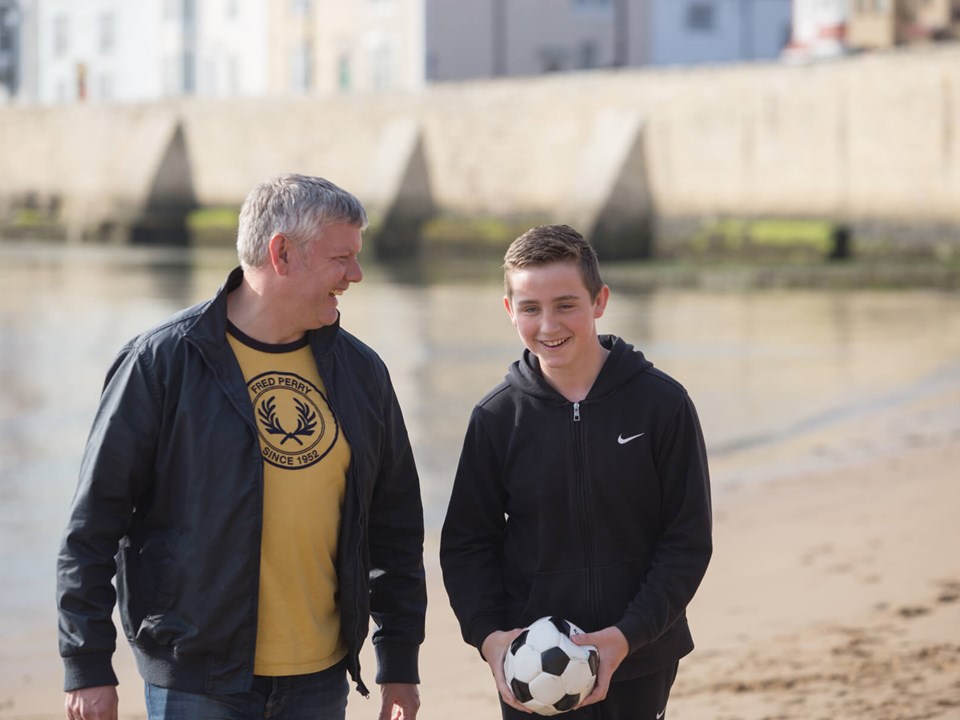Man and Boy on Beach with Inflatable football